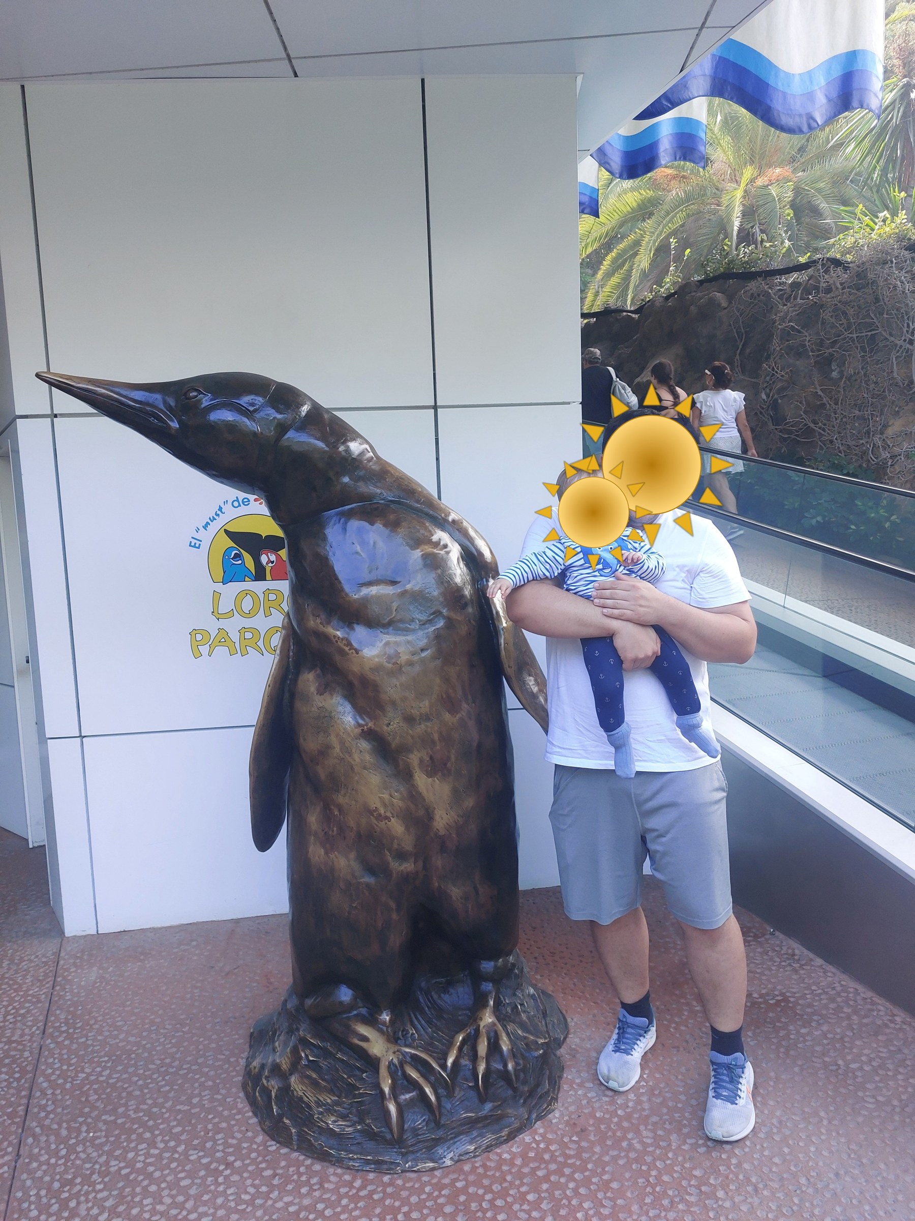 Papa und Lolo am Pinguin-Denkmal im Loro Parque, Teneriffa (Gesichter mit Sonne verdeckt)
