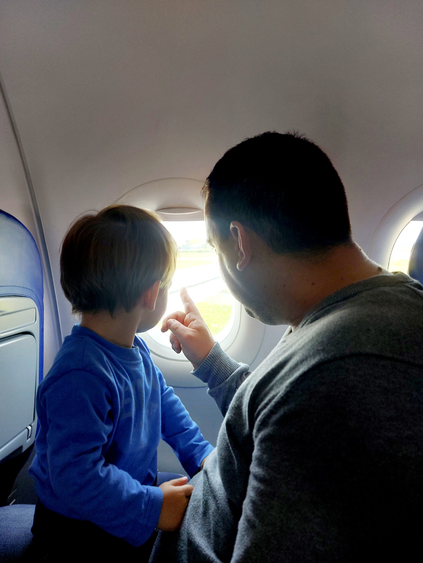 Papa und Lolo schauen gemeinsam aus dem Flugzeugfenster auf dem Weg nach Hermannstadt (Gesichter mit Sonne verdeckt)