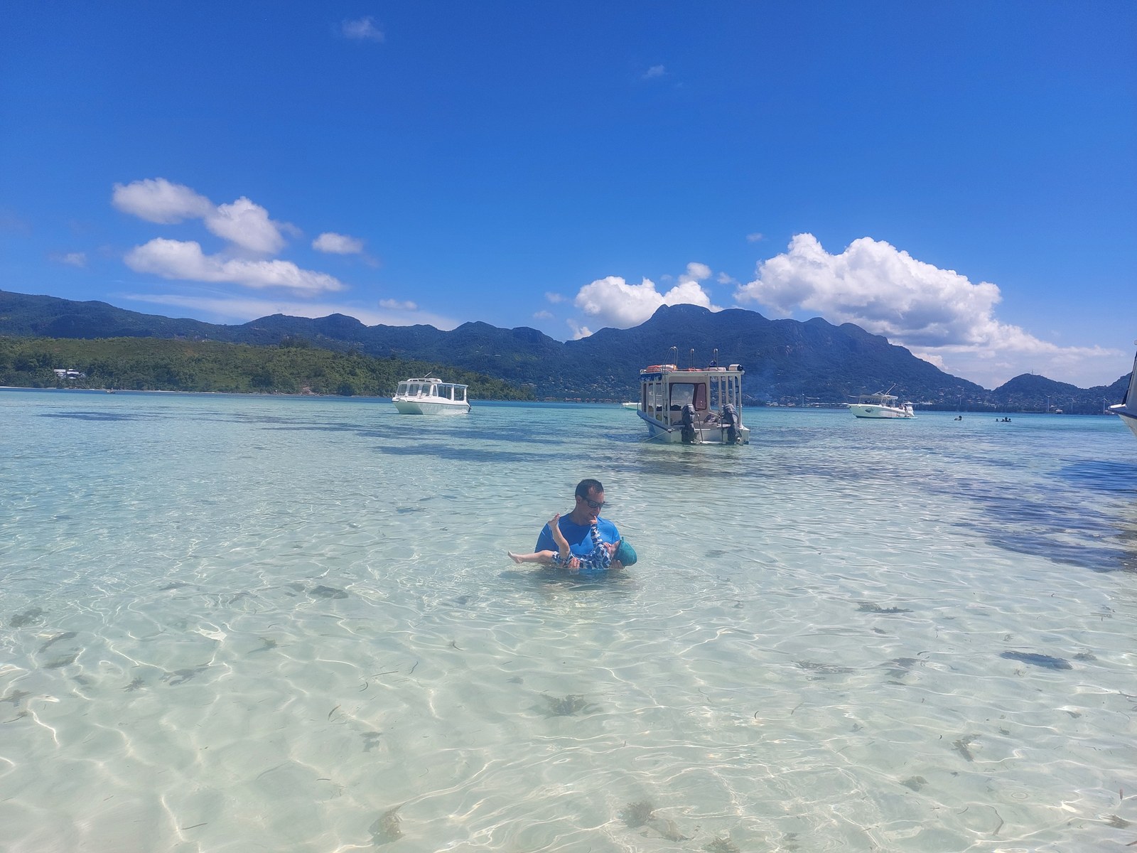 Familie im klaren Wasser der Seychellen (Gesichter mit kleinen Sonnen markiert)