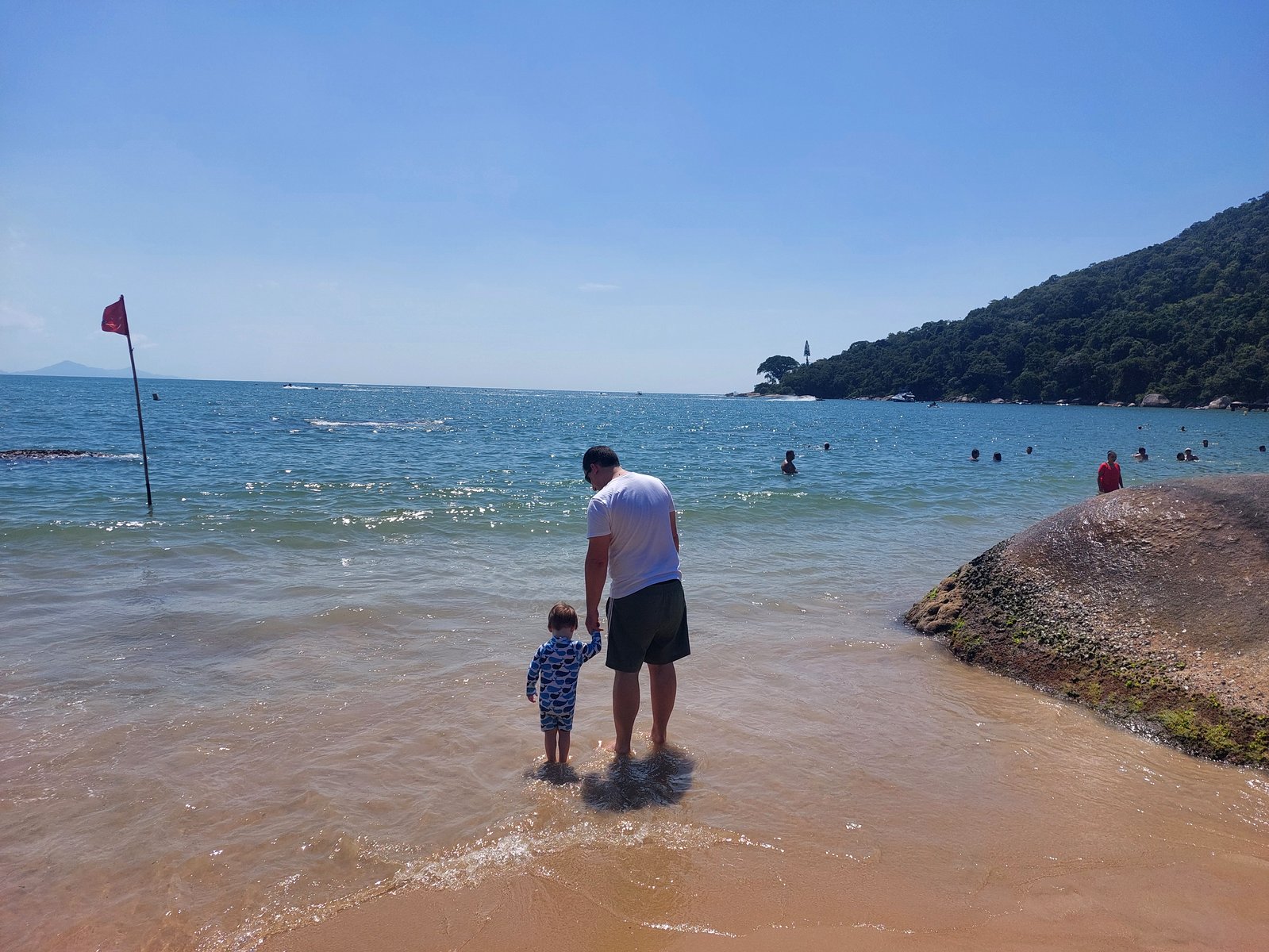 Papa und Lolo waten gemeinsam im Wasser am Praia de Laranjeiras (von hinten)