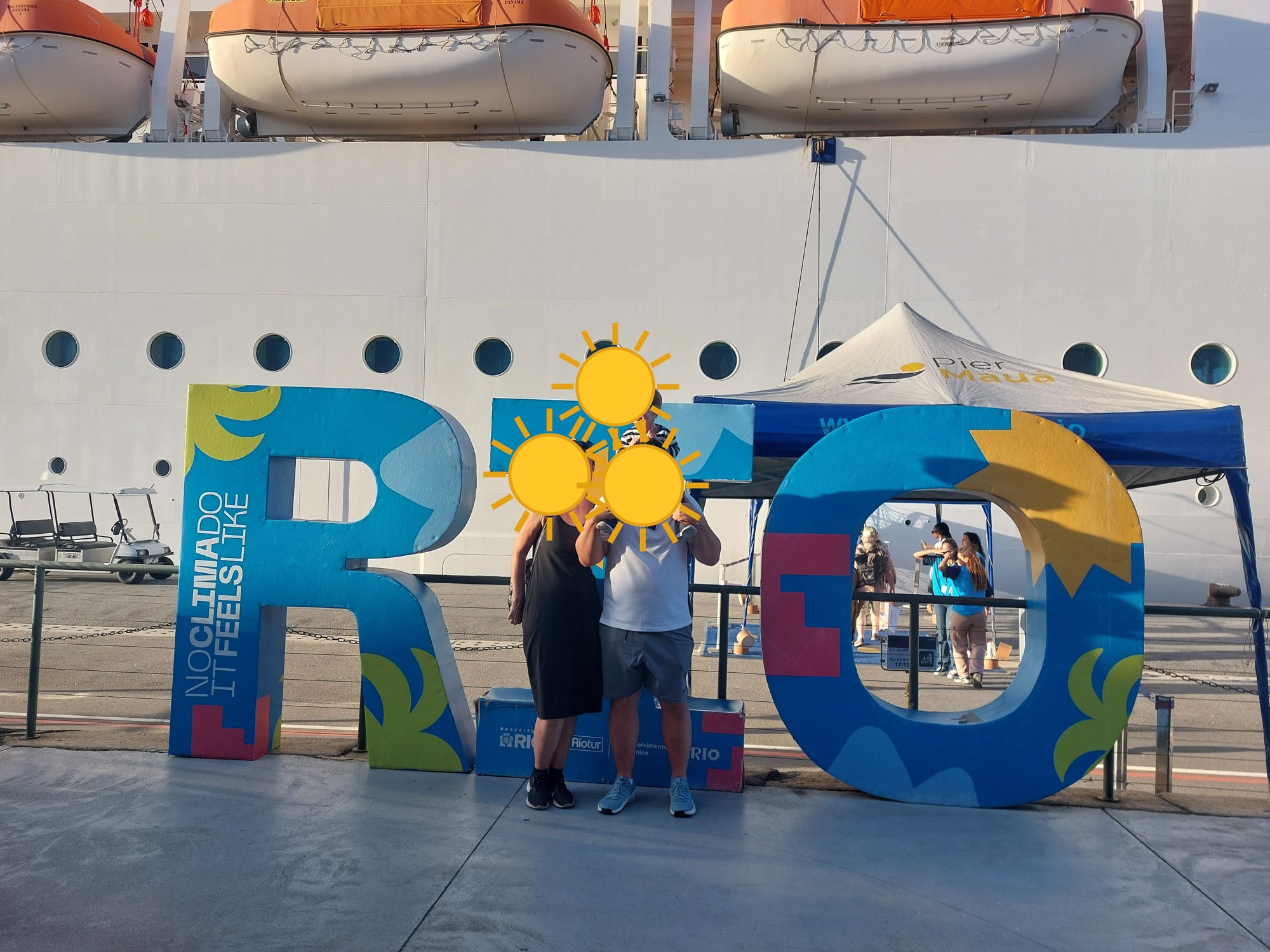 Familie vor dem RIO-Schild am Hafen vor dem Kreuzfahrtschiff (Gesichter mit Sonne verdeckt)