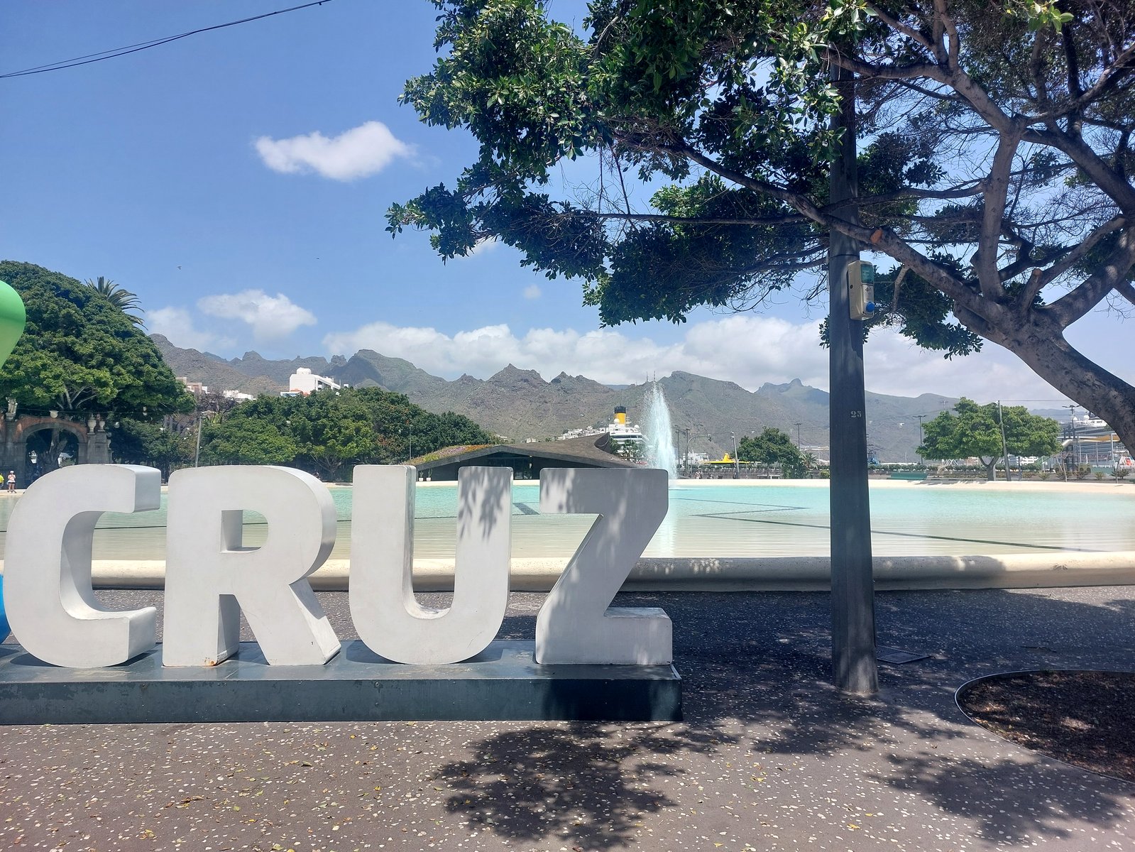 CRUZ Schriftzug in Santa Cruz de Tenerife mit Teich und Kreuzfahrtschiff im Hintergrund