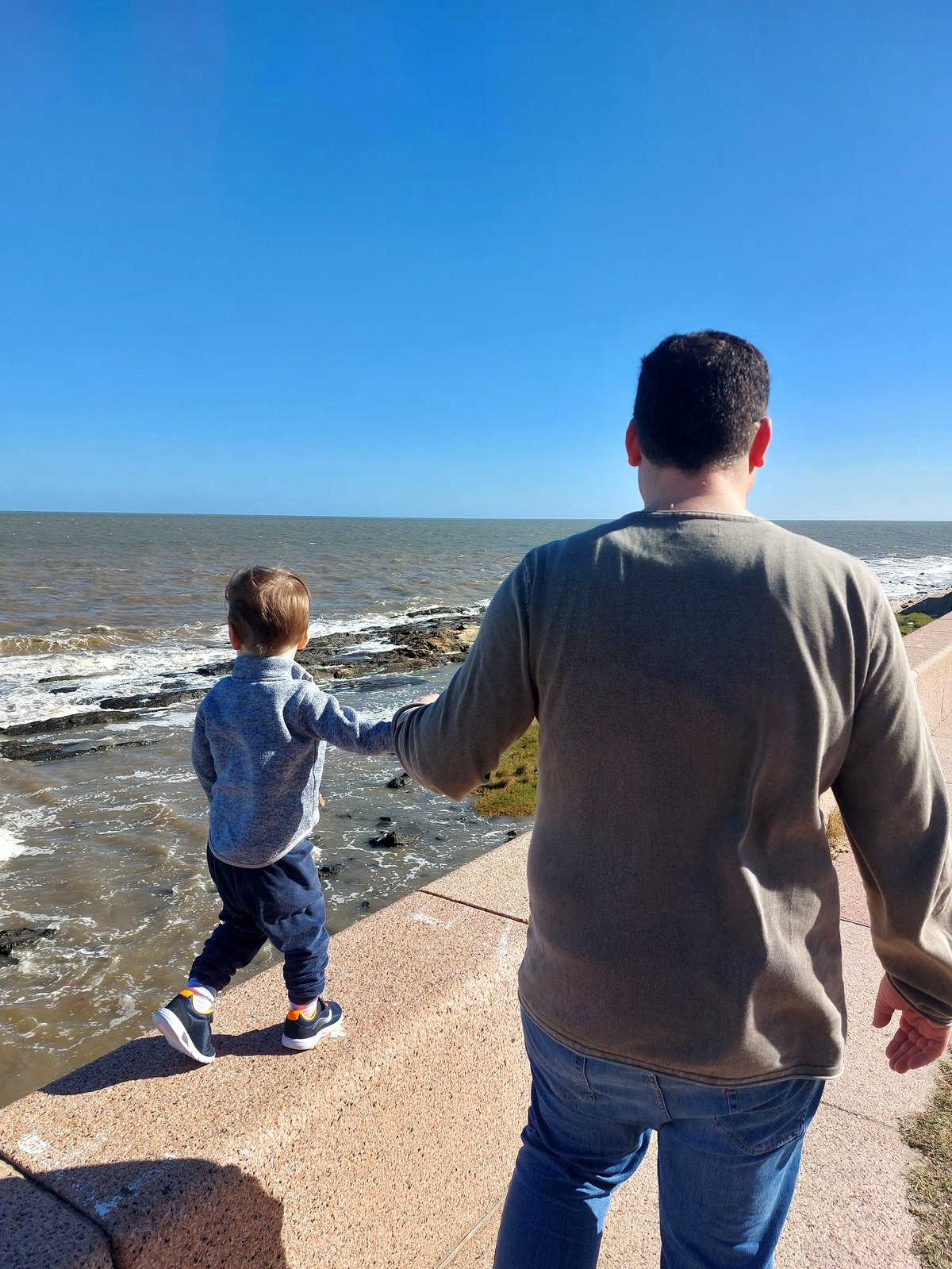 Papa und Lolo schauen gemeinsam aufs Meer in Montevideo (von hinten)